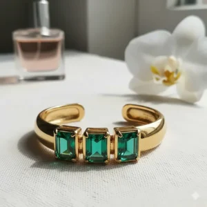 A stylish gold and emerald bangle bracelet, a modern take on this luxurious gemstone jewelry.