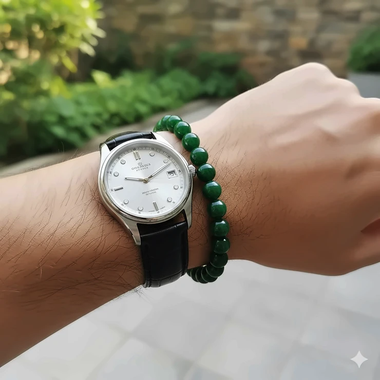 A handsome mens jade bracelet with polished green stones, perfectly accessorizing a man's watch on his wrist.