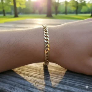 Natural sunlight reflecting off a men's gold Figaro chain bracelet worn during a casual outing.