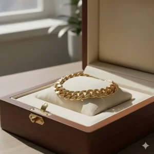 A men's gold Figaro chain bracelet presented in a luxury wood-grain gift box.