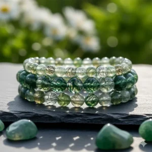 A stack of three different moss agate bead bracelets showing a variety of light and dark green patterns.