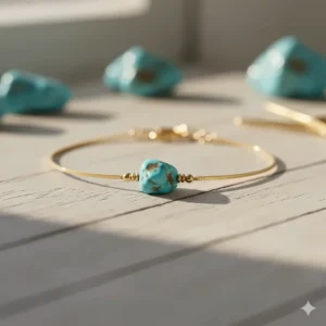 Close-up detail of raw natural turquoise stones in a dainty gold chain bracelet.