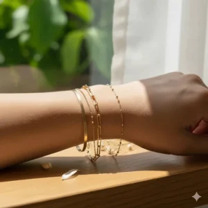 A stack of gold jewelry featuring a paperclip chain bracelet paired with a thin gold cuff.