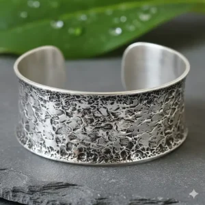 Close-up texture of a handcrafted hammered silver wide statement cuff bracelet.