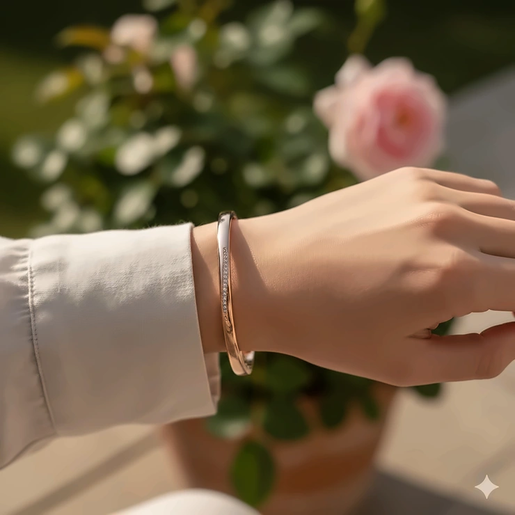 A woman wearing a luxury rose gold bangle bracelet on her wrist, styled with a neutral-toned outfit. rose gold bracelet women