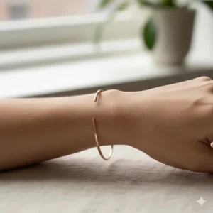 A dainty rose gold minimalist cuff bracelet worn on a female wrist.