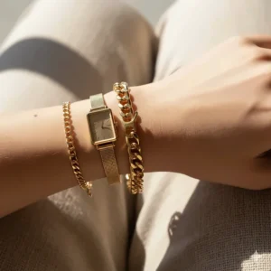 A trendy stack of chunky gold chain bracelets for women paired with a delicate gold watch.