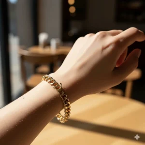 Side view of a chunky gold chain bracelet on a woman's wrist showing the lobster claw clasp.