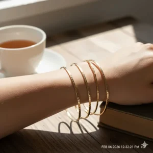 Three thin hammered gold bangle bracelets stacked together for a layered jewelry look.