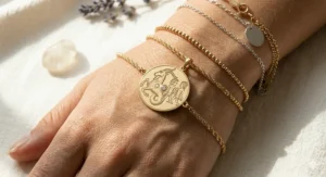 Macro shot of a high-quality hand-engraved zodiac sign charm featuring the Capricorn and Gemini symbols on a gold bracelet.