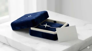 A minimalist silver cross charm bracelet presented in a luxury blue velvet gift box for women.