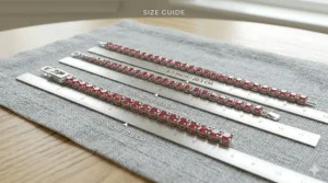 A size guide showing ruby tennis bracelets in various lengths (7.0, 7.5, and 8.0 inches) on a measuring scale.