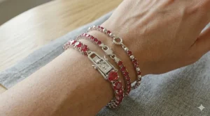 Three ruby tennis bracelets in sterling silver stacked on a wrist to demonstrate different stone sizes and styles.