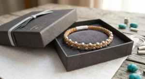 Handmade leather bracelet with silver beads resting inside a luxury cardboard gift box with a ribbon.