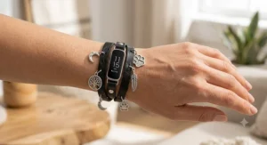 Black leather wrap jewelry bracelet with decorative silver charms attached to a Fitbit Inspire