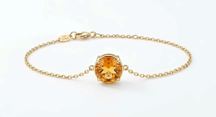 A delicate 14k gold chain bracelet featuring a faceted round November birthstone citrine charm, isolated on a white background. november birthstone citrine bracelets