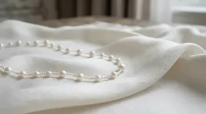 A minimalist single-strand akoya pearl bracelet styled on smooth silk fabric